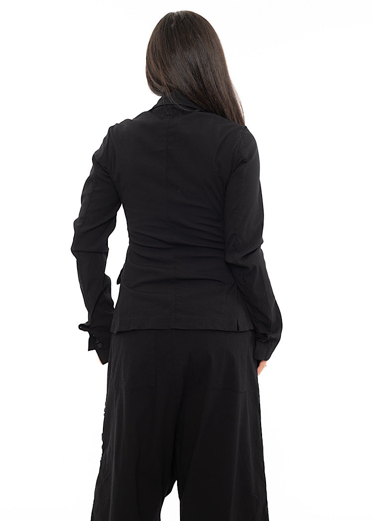 A Model standing facing the back wearing a minimalist techno Jacket with rouging details. Showing the design of the jacket from behind.
