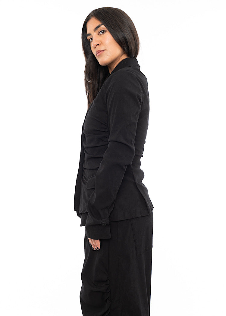 A Model standing to the side wearing a minimalist techno Jacket with rouging details. Showing the fitted design of the piece.
