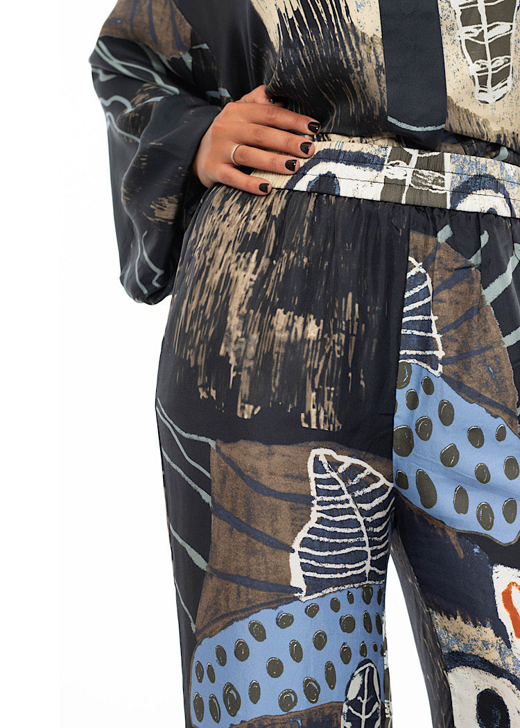 A close up off a model wearing a wide leg Silk trousers. Standing facing the front showing the waistband and tuck in effect of matching shirt.