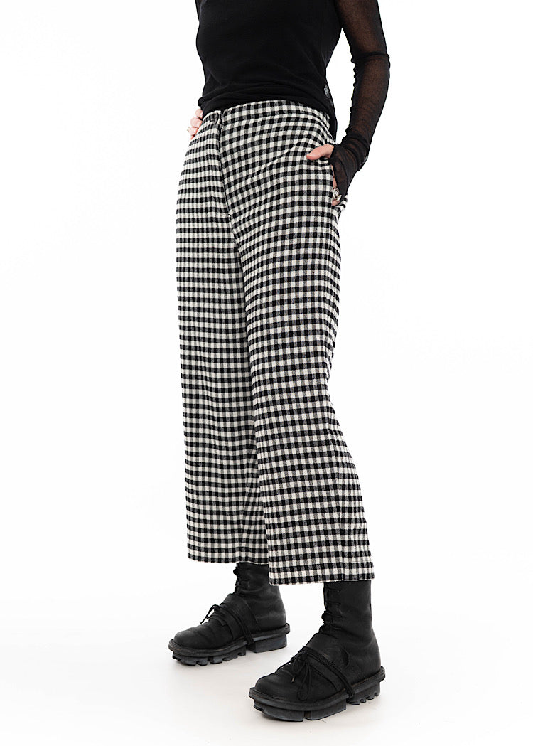 Model wearing black and white gingham check wide-leg trousers with side pockets, cropped ankle length, styled with black top and black combat boots